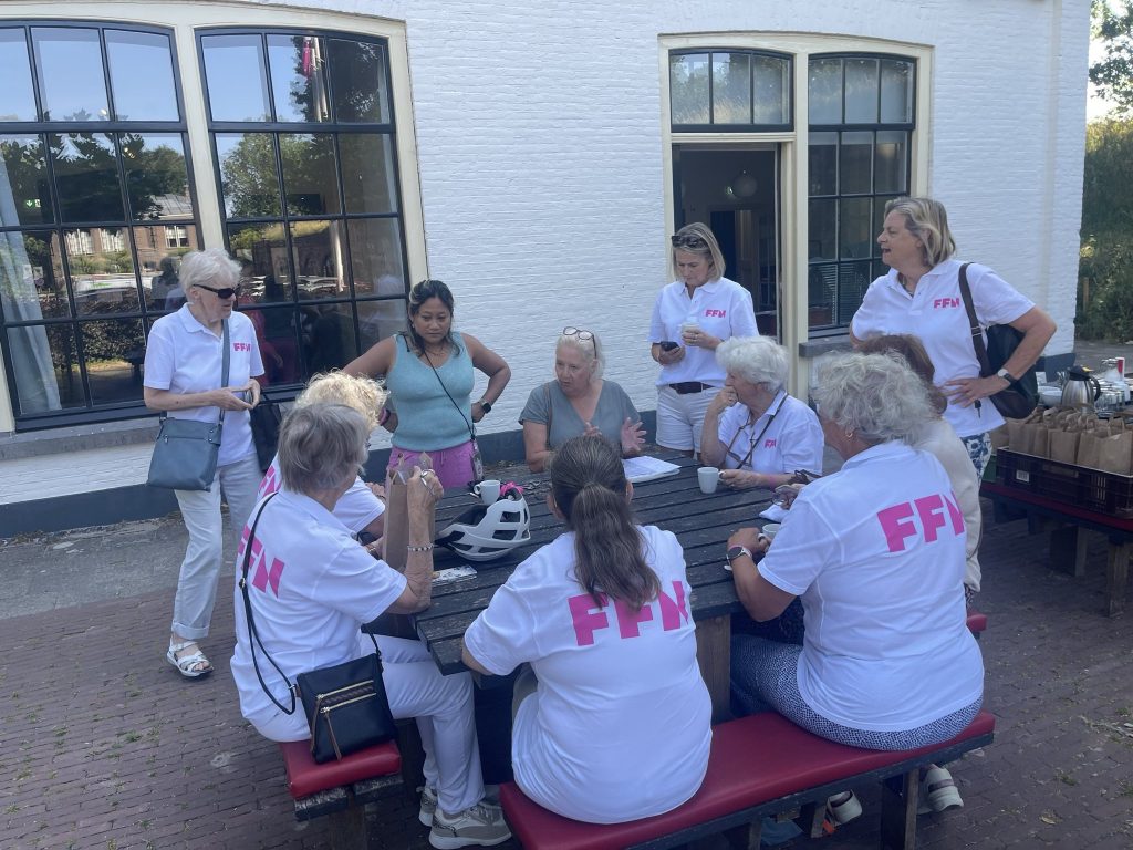 Vrijwilligers in FFN-shirts overleggen aan een picknicktafel