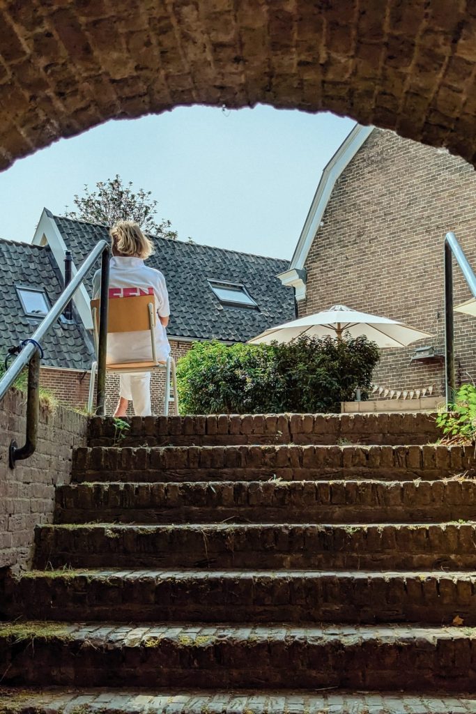 Vrijwilliger in FFN-shirt op een stoel boven aan een stenen trap